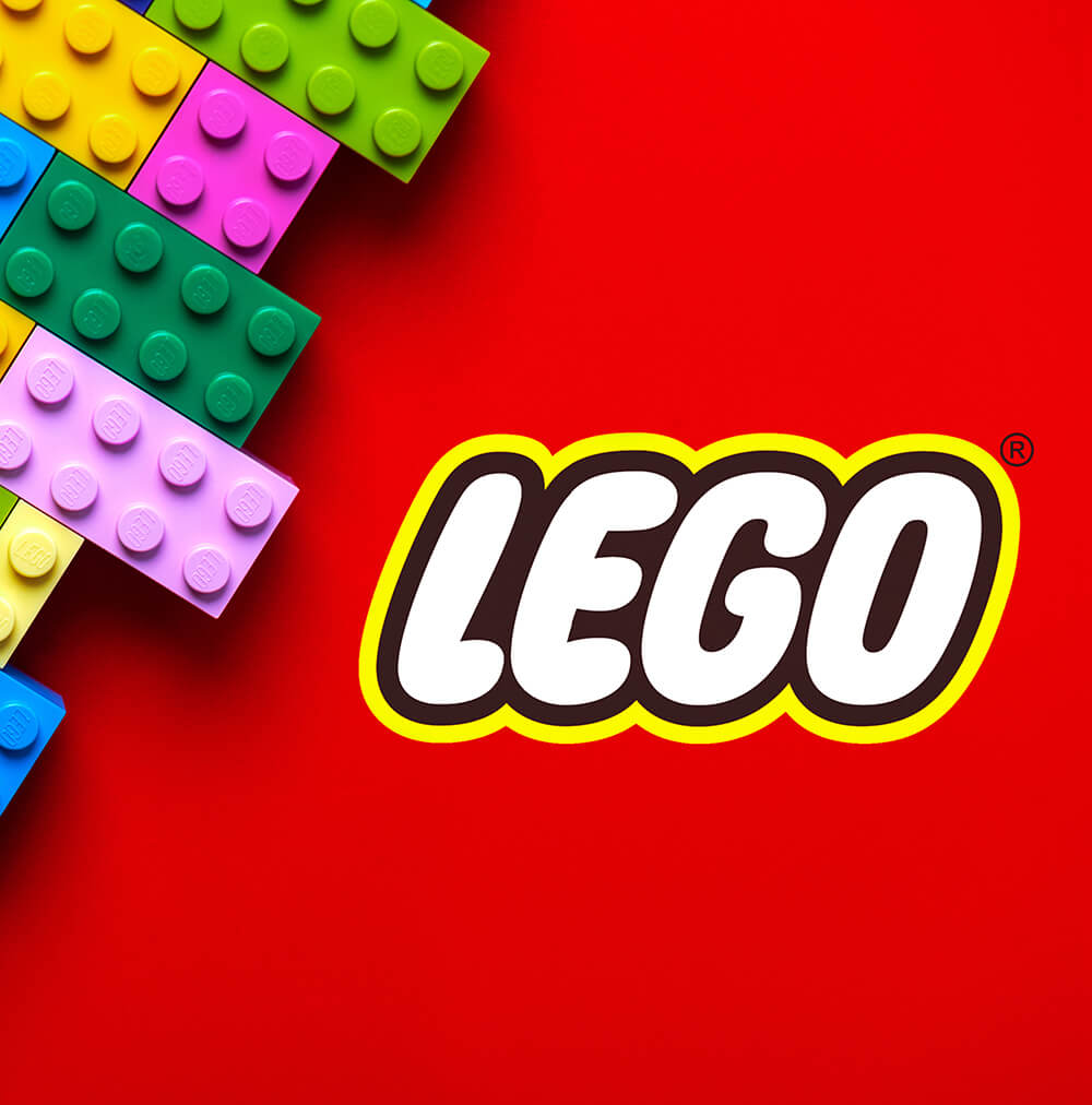 LEGO logo displayed on a bright red background alongside colorful LEGO bricks, illustrating the consistent visual identity that has remained recognizable as the brand expanded into entertainment, education, and digital experiences.